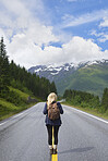 Adventure backpacking woman travels on road in epic majestic mountain snow landscape