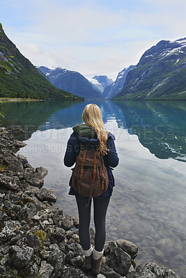 Buy stock photo Backpack, mountain and woman by river in nature for winter vacation, destination or holiday. Travel, snow and female person by lake for outdoor scenery on weekend trip with sustainable location.