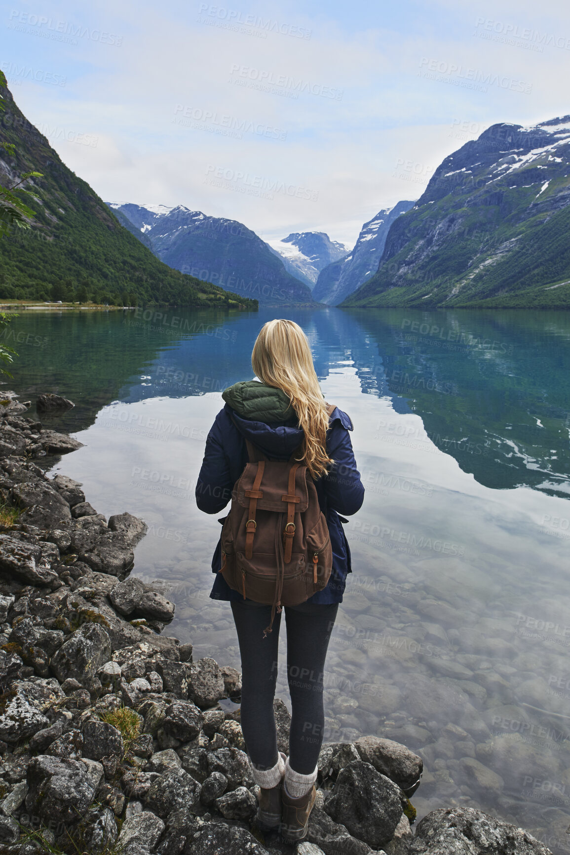 Buy stock photo Backpack, mountain and woman by river in nature for winter vacation, destination or holiday. Travel, snow and female person by lake for outdoor scenery on weekend trip with sustainable location.