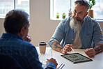 two businessmen using tablet computer discussing financial graph data on mobile touchscreen device in meeting