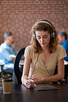 beautiful woman using tablet computer with stylus pen listening to music wearing headphones