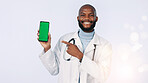 Black man, green screen and portrait of doctor with phone in studio for medical app for consultation. Tech, pointing and healthcare worker with cellphone for appointment booking by white background.