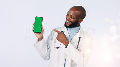 Buy stock photo Black man, green screen and doctor pointing with cellphone in studio for medical app on mockup space. Tech, bokeh and healthcare worker with phone for appointment booking display by white background.