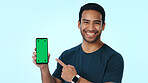 Green screen, portrait and happy man with phone, pointing and recommendation for social media or web. Blue background, online and person with smile for mobile, promotion and technology in studio 