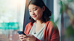 Happy, typing and Asian woman with phone in home for social media, online chat and notification. Apartment, scroll and person on smartphone for connection, communication and message on mobile app