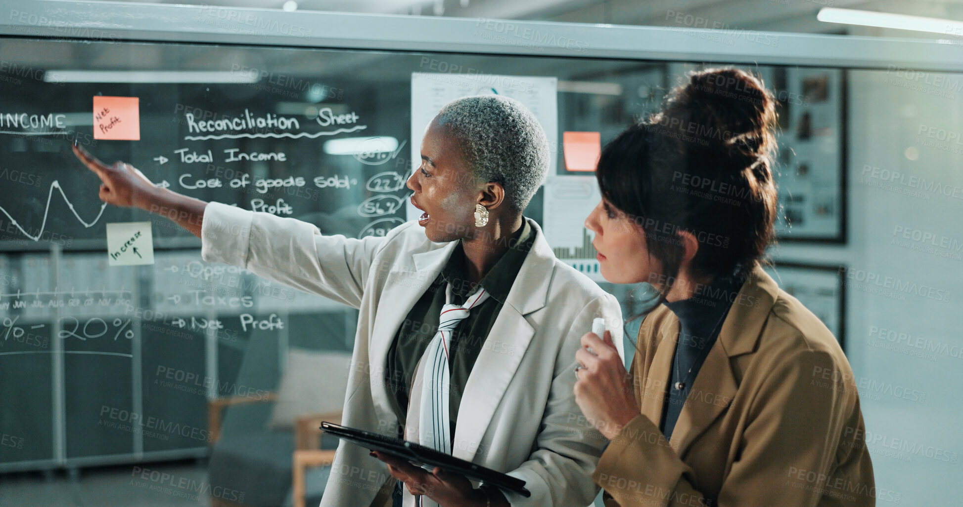 Buy stock photo Women, tablet and team at glass wall in office at night, graphs and reconciliation sheet at finance company. Business people, tech and app at window, feedback or review for asset management agency
