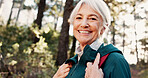 Hiking, senior woman and portrait in woods for adventure, retirement hobby and cardio wellness. Mature person, smile and vacation with backpack for trekking, explore and holiday sightseeing in forest