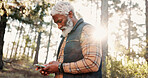 Hiking, phone and senior black man in forest for wellness, fresh air and online map for direction. Travel, morning and elderly person on nature trail for search, health and exercise on smartphone