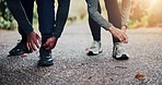 Hands, fitness and tying shoes with people outdoor together for cardio training or workout. Exercise, feet and laces with runners on ground in nature for bonding, health or wellness activity