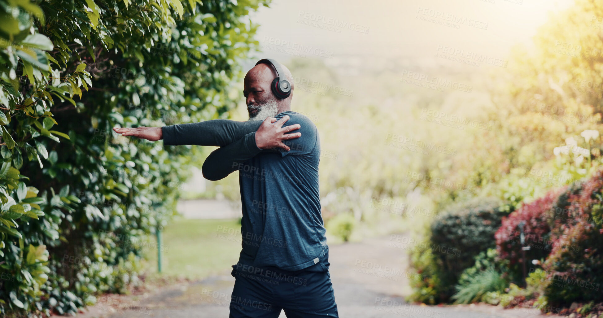 Buy stock photo Stretching, fitness and headphones with black man in nature for runner playlist, streaming and health. Workout podcast, muscle warm up and training with senior person outdoor for wellness and radio