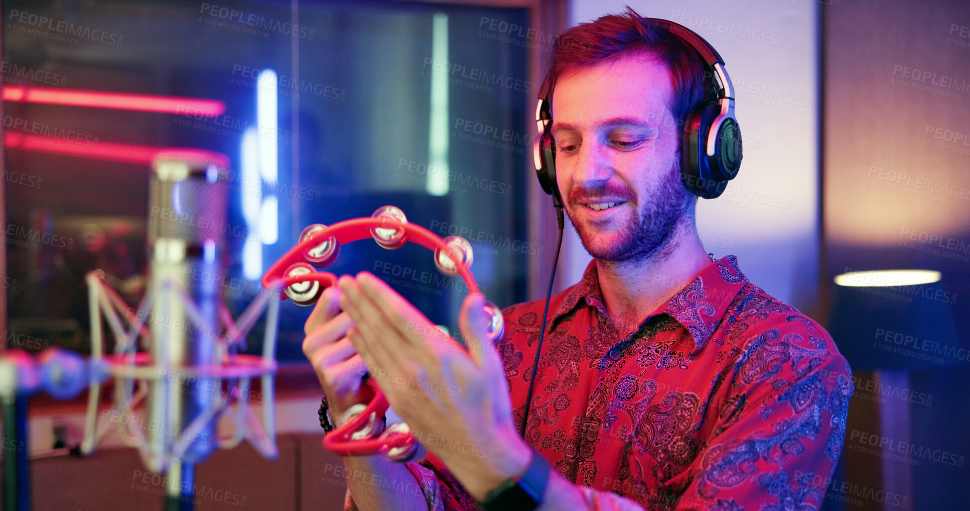 Buy stock photo Music, production and man with tambourine in studio for entertainment, recording and sound media. Artist, headphones and musician in neon with microphone for audio, broadcast or performance of song