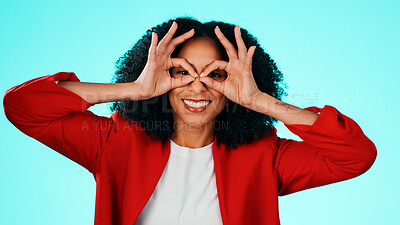 Buy stock photo Binocular, hands and woman with expression portrait in studio for playful gesture, vision or funny face. Happy female person, comic finger glasses and blue background for joke, frame or perspective
