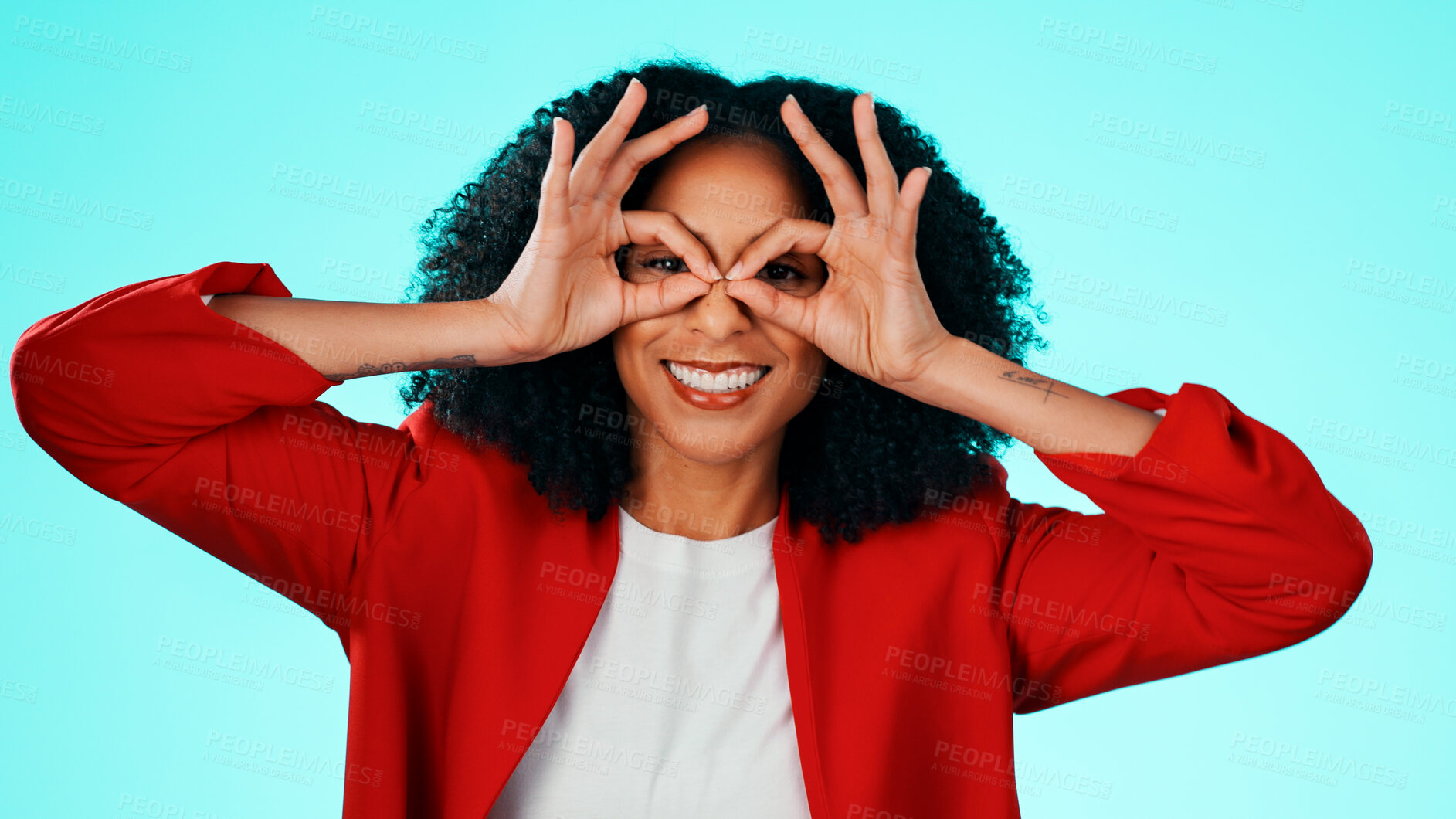Buy stock photo Binocular, hands and woman with expression portrait in studio for playful gesture, vision or funny face. Happy female person, comic finger glasses and blue background for joke, frame or perspective