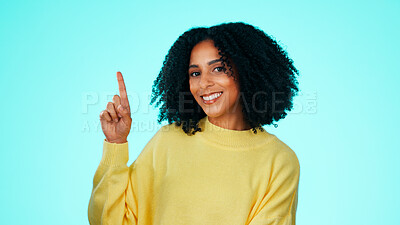 Buy stock photo Woman, portrait and pointing up in studio for advertising, marketing and mockup for announcement. Happy, female person and hand gesture with surprise news, promo or discount sale on blue background