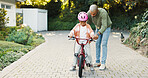 Balance, help and father teaching daughter how to ride bicycle outdoor in front of home. Protection, push and safety of girl child with single parent man in driveway for cycling activity or learning