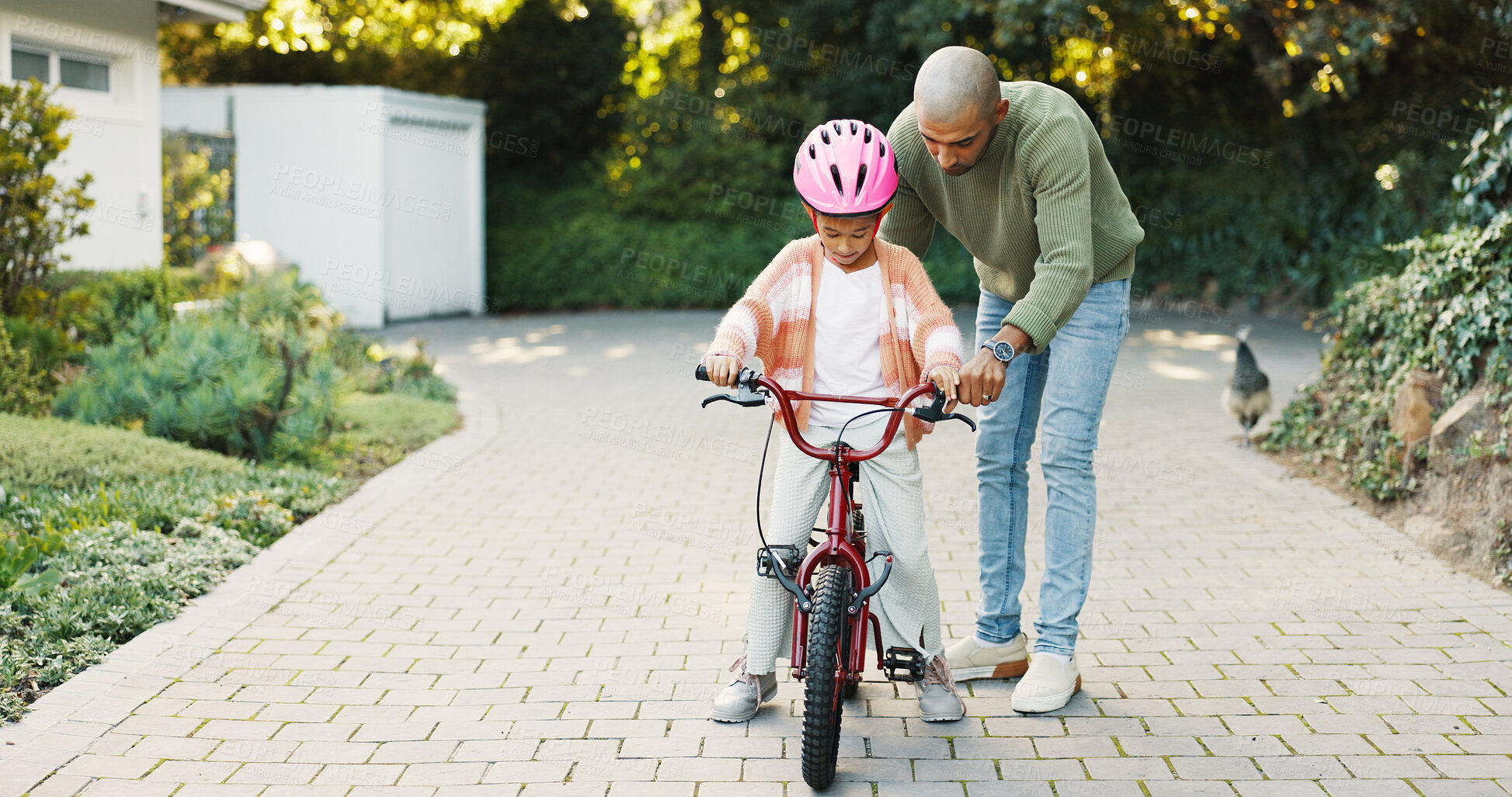Buy stock photo Cycling, help and father teaching daughter how to ride bicycle outdoor in front of home. Bike, protection and safety of girl child with single parent man in driveway for activity, balance or learning
