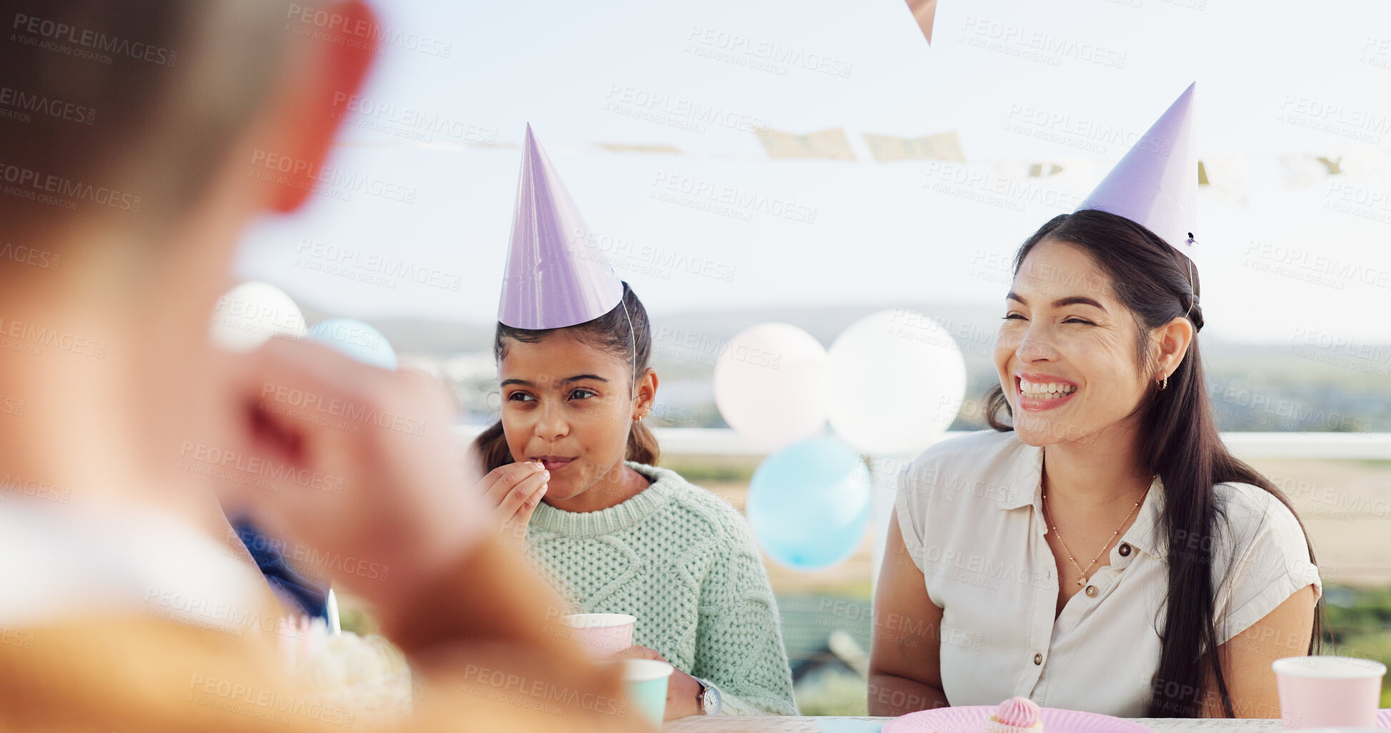 Buy stock photo Happy people, family and birthday with party hat for outdoor celebration together at table. Excited, group or laughing with smile, balloons or milestone for another year, wishes or social gathering