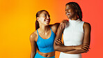 Women, friends and laugh in studio for fitness, bonding and funny joke with space on orange background. People, smile and conversation at exercise club, wellness and story with partnership for gym