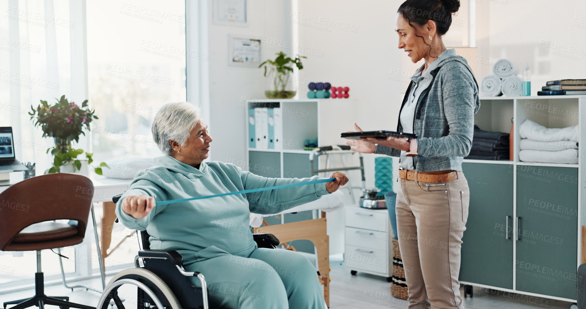 Buy stock photo Old woman, physiotherapist and tablet with resistance band in wheelchair for exercise, guide or injury at clinic. Elderly person with disability, strength training and caregiver with rehabilitation