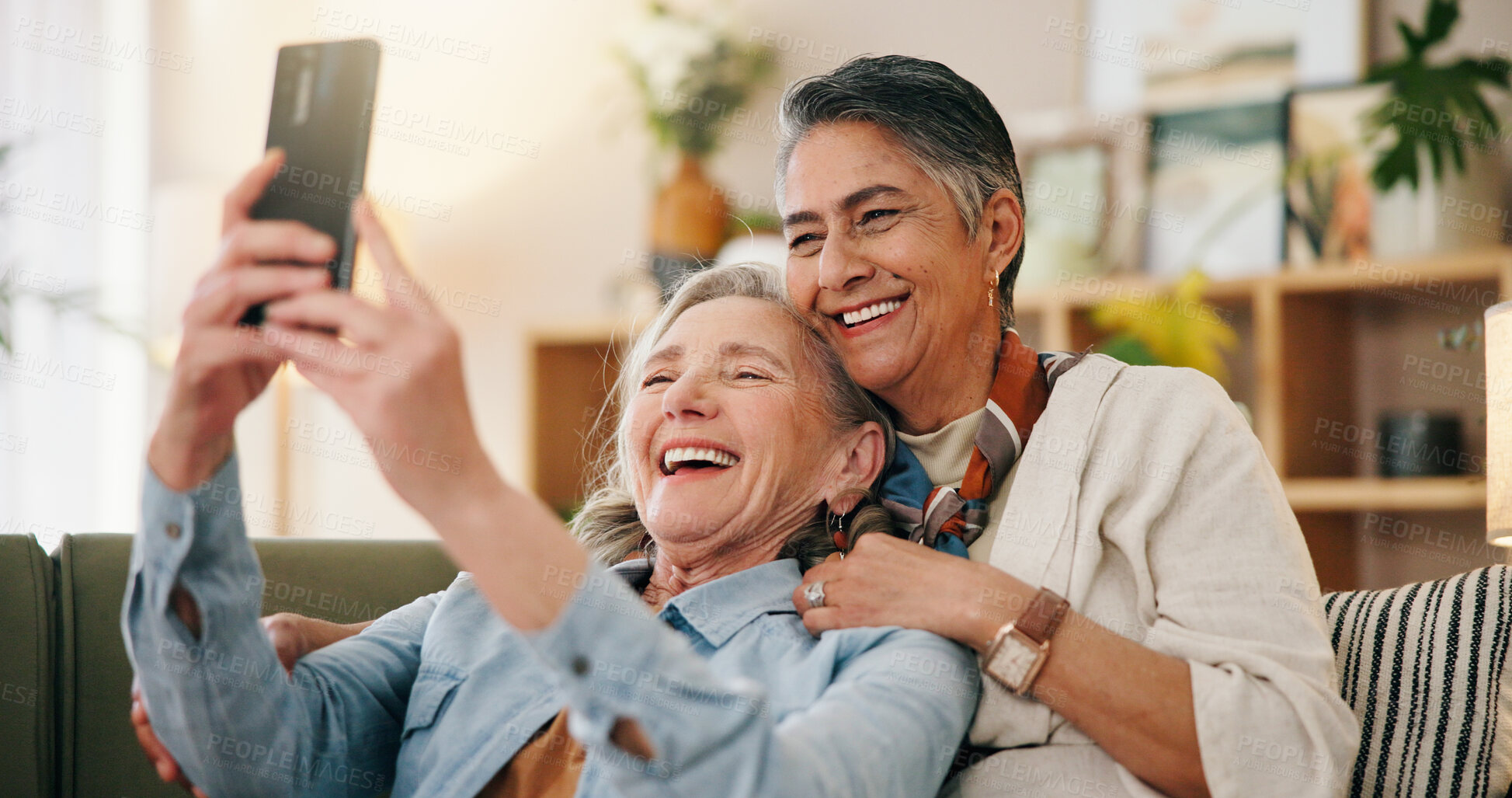 Buy stock photo Mature, happy couple and hug with selfie on sofa for picture, photography or memory together in home. Female people, LGBTQ or lesbians with smile for capture moment, funny post or social media app