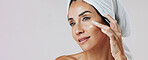 Skincare, thinking and woman with cream in studio, apply retinol moisturizer and anti aging treatment. Banner, reflection and mature person with lotion for glowing skin, space and white background