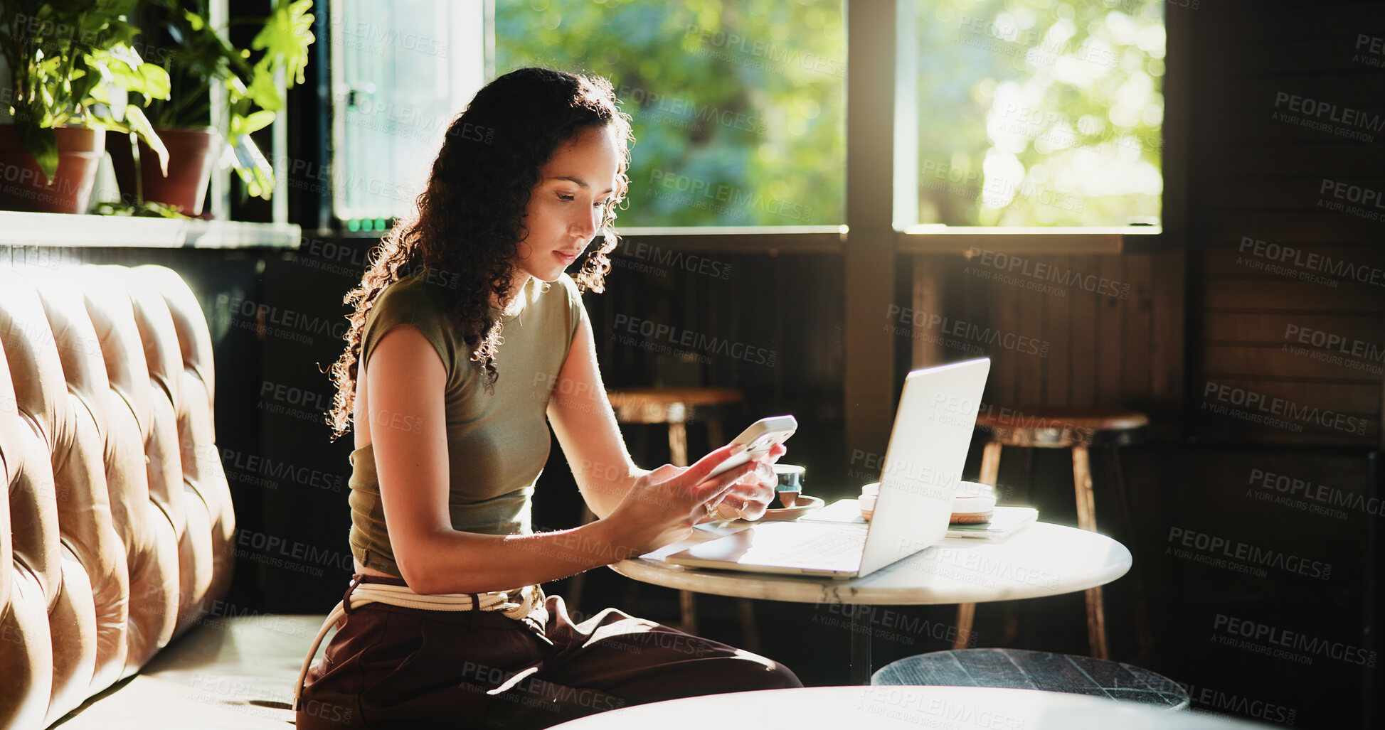 Buy stock photo Woman, phone and laptop in coffee shop for remote work, trend research and lunch break. Female person, tech and thinking in cafe for freelance, communication and social networking in small business