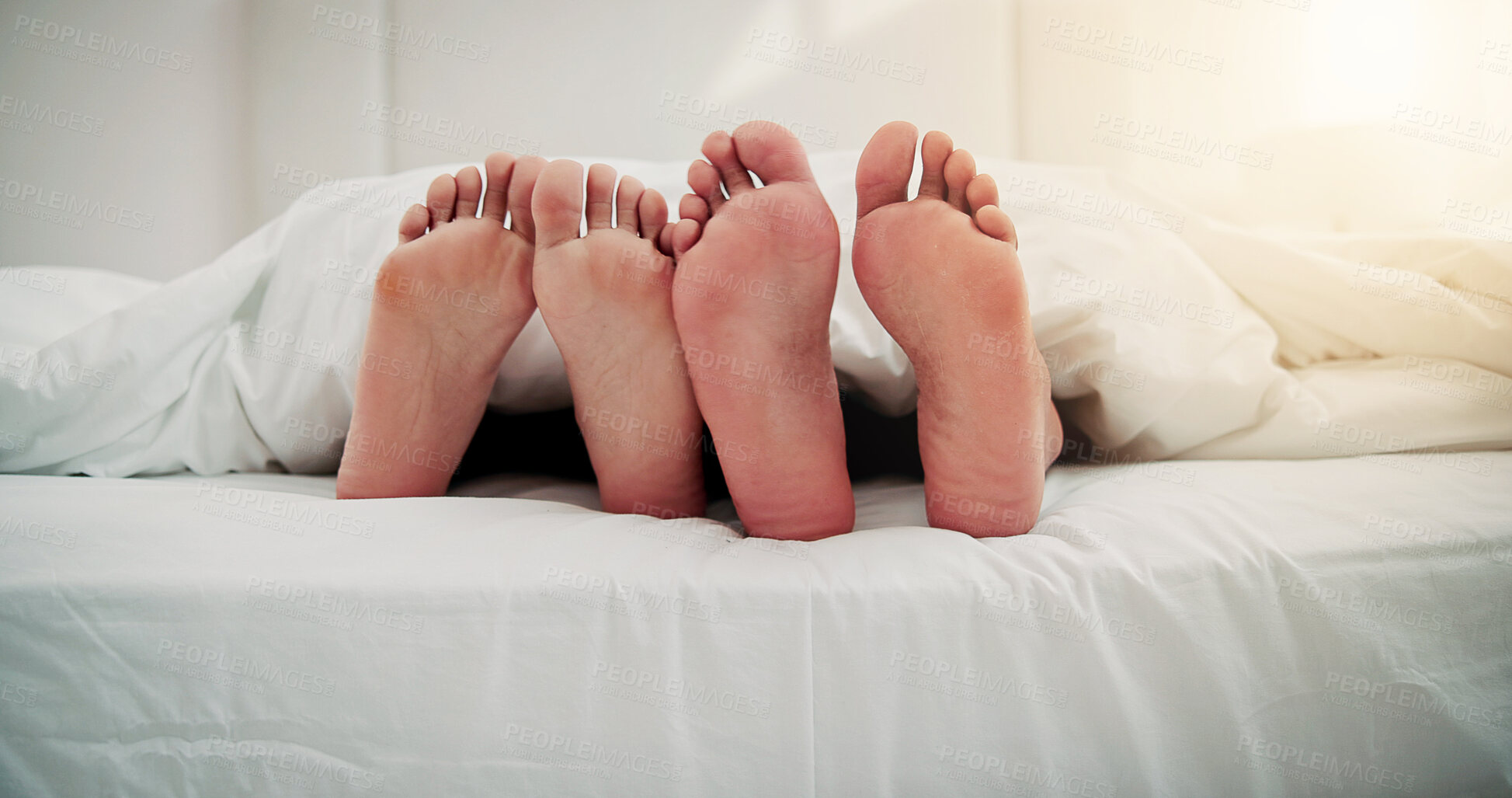Buy stock photo Home, sleep and feet of couple in bed for resting, love and relax together in morning. Apartment, weekend and people with blanket, duvet and barefoot for cuddle, bonding and relationship in bedroom