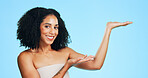 Studio, portrait and happy woman with presentation for skincare, promotion and cosmetics for beauty. Blue background, dermatology and person with smile for recommendation, healthy skin and marketing