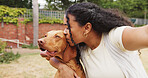 Selfie, woman and kiss dog in backyard with hug, animal care or trust companion for bonding together. Person, puppy and embrace in home garden with affection, connection and photography for memories.