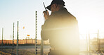 Security, man and outdoor with radio for communication, surveillance and guard by fence with flare. Protection, service and back of person with tech for safety, perimeter search or patrol at sunset