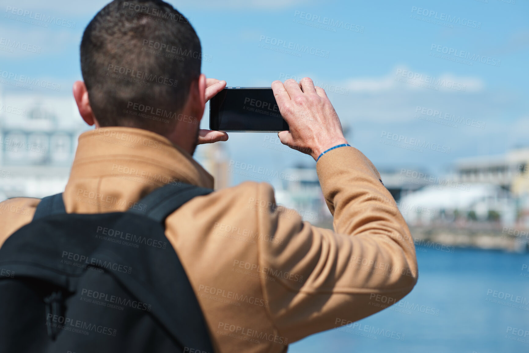 Buy stock photo Photo, back and man in town with phone, online memories or post update on weekend travel. Digital, tourism and male person at harbor with tech, social media picture or memory capture on outdoor trip.