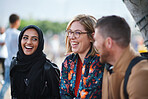 Multiracial friends hanging out sitting on bench in city chatting 