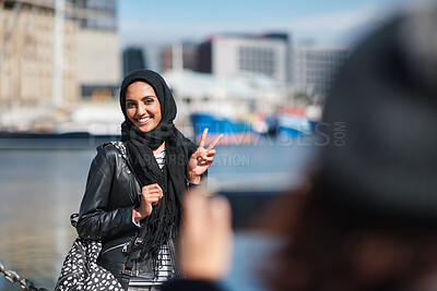 Buy stock photo Travel, happy and muslim woman with photography in city for memory on vacation, getaway or holiday. Smile, peace sign and islamic female person with hijab for picture on weekend trip in urban town.