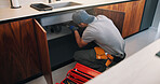 Plumber, man and maintenance on kitchen sink with tools, pipe repair and check for quality assurance. Handyman, person and plumbing work in home with equipment, fix leak and inspection from back.