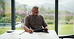 Bills, paperwork and black man on tablet in home for finance review, online payment and expenses. Documents, writing and mature person on tech for digital banking, budget planning or financial report