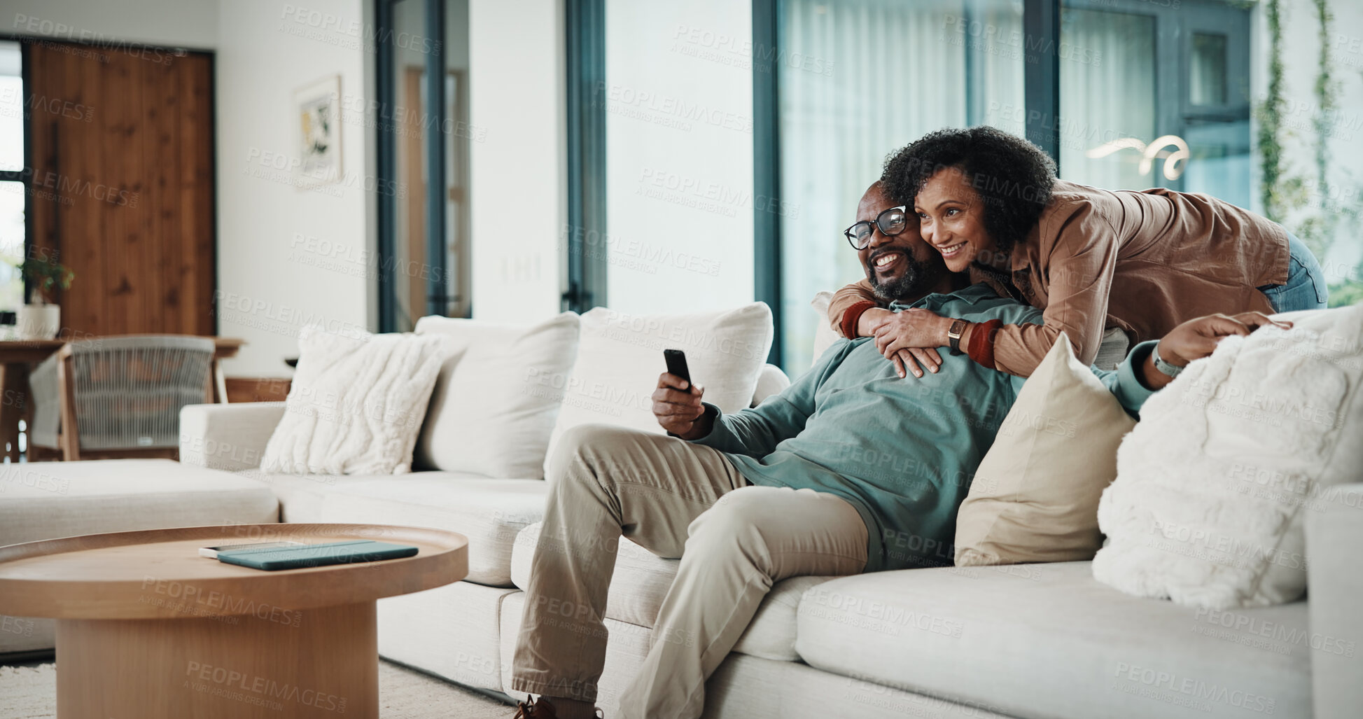 Buy stock photo Couple, hug and watching tv on couch, home and bonding with partner on weekend and streaming movies. Mature African people, love and connection with spouse on break, smile and relax together in house