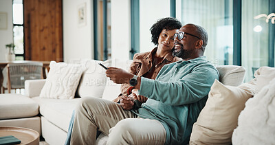 Buy stock photo Couple, remote and watching tv on couch, lounge and bonding with partner or happy on weekend in home. Mature African people, love and connection with spouse, smile and change channel with controller