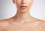 Closeup of a beautiful mixed race woman's perfect neck and collar bone to model jewellery. A hispanic woman's flawless pout wearing pink lipgloss against grey studio copyspace background