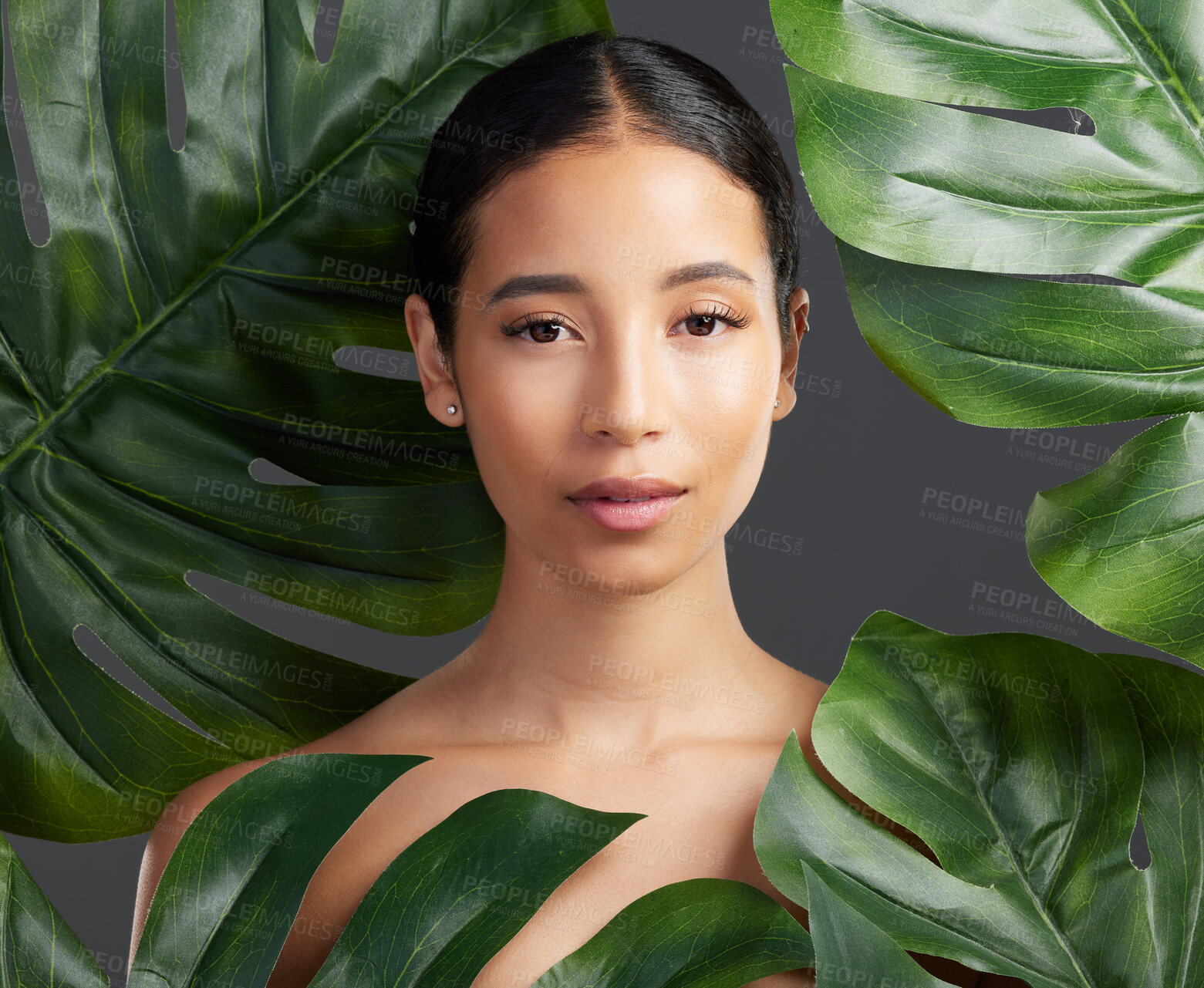 Buy stock photo Portrait, woman and beauty in studio with leaves, natural skincare and sustainability for wellness. Person, monstera plant or organic cosmetics for dermatology, self care and glow on gray background.