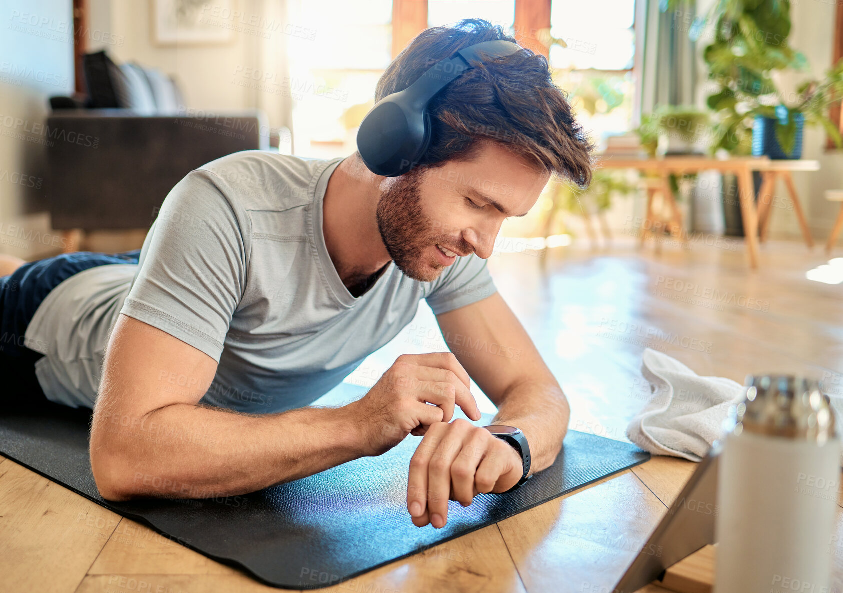 Buy stock photo Man, relax and smart watch at house for fitness progress, monitor heartbeat and health stats. Smile, person and headphones with wristwatch, exercise results and performance information for wellness