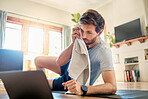 One fit young caucasian man wiping sweat off forehead with a towel while taking a break from exercise at home. Guy looking tired while training with online workout tutorials on digital tablet
