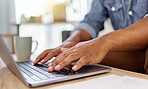 Closeup of a man&rsquo;s hand typing an email while working on a laptop alone at home. One person using a laptop on a table in the lounge at home