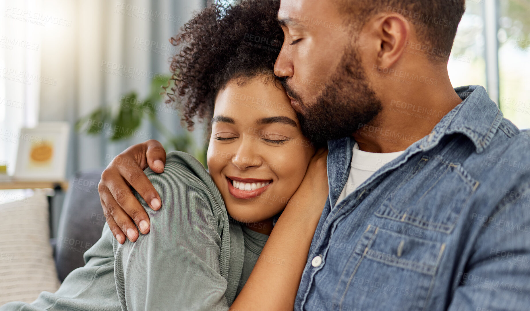 Buy stock photo Couple, kiss and love in home with smile for bonding, connection and trust in marriage. Embrace, affection and happy together with African people in house for commitment, support and moment on sofa