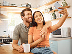 Young cheerful interracial couple taking a selfie with a phone together at home. Joyful caucasian boyfriend and mixed race girlfriend taking a photo on a cellphone. Happy husband and wife relaxing and spending time together in the morning