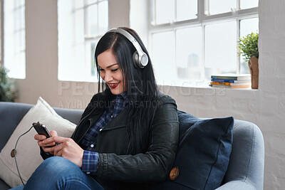 Buy stock photo Phone, headphones and woman in office with texting, networking or social media on mobile app. Happy, audio tech and female designer on sofa with cellphone for chatting online at startup agency.