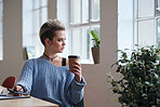 Beautiful woman looking out window using smartphone holding cup of coffee relaxing at home