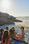 Mixed race group of diverse friends eating watermelon on the beach at sunset