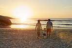 Mother Father and Daughter holding hands walking towards sunset