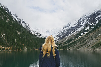 Buy stock photo Back, woman and mountain with lake, winter holiday and sightseeing exploration for outdoor adventure. Person, hiking and peace by river with scenic view, cold climate and snow for travel vacation.