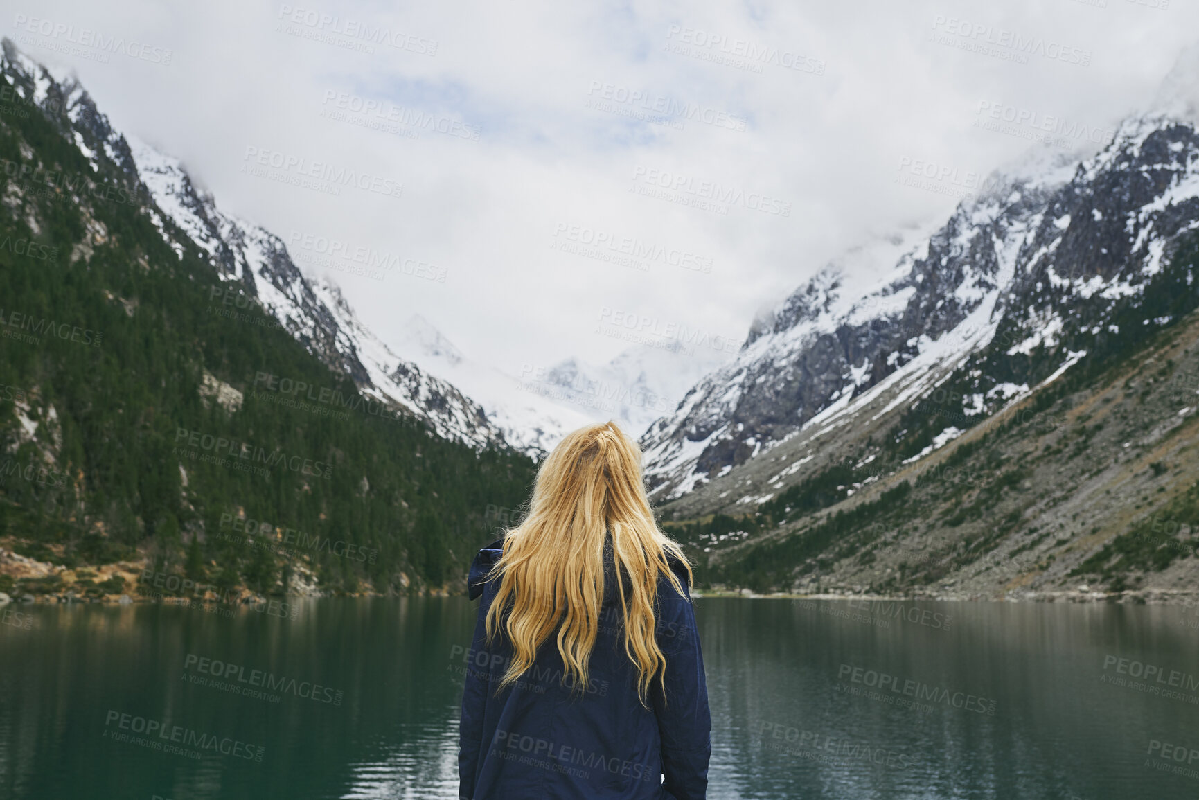 Buy stock photo Back, woman and mountain with lake, winter holiday and sightseeing exploration for outdoor adventure. Person, hiking and peace by river with scenic view, cold climate and snow for travel vacation.